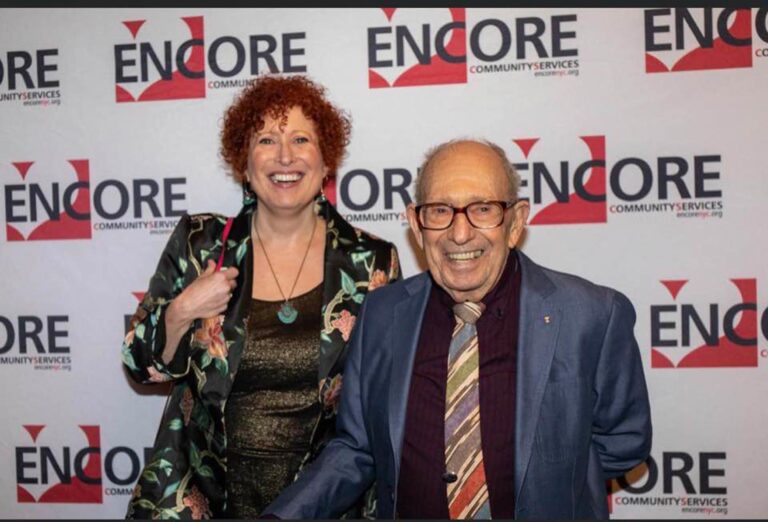 Well dressed couple standing in front of an Encore banner